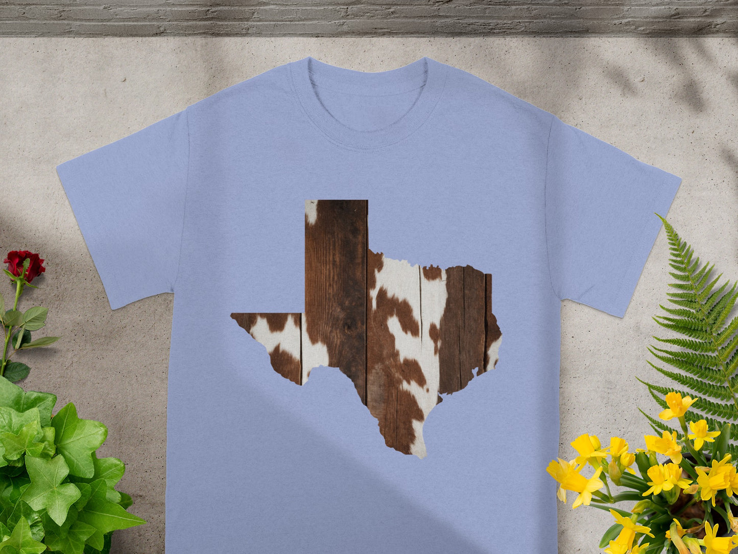 Light blue t-shirt with Texas silhouette filled with cowhide and wood pattern.
