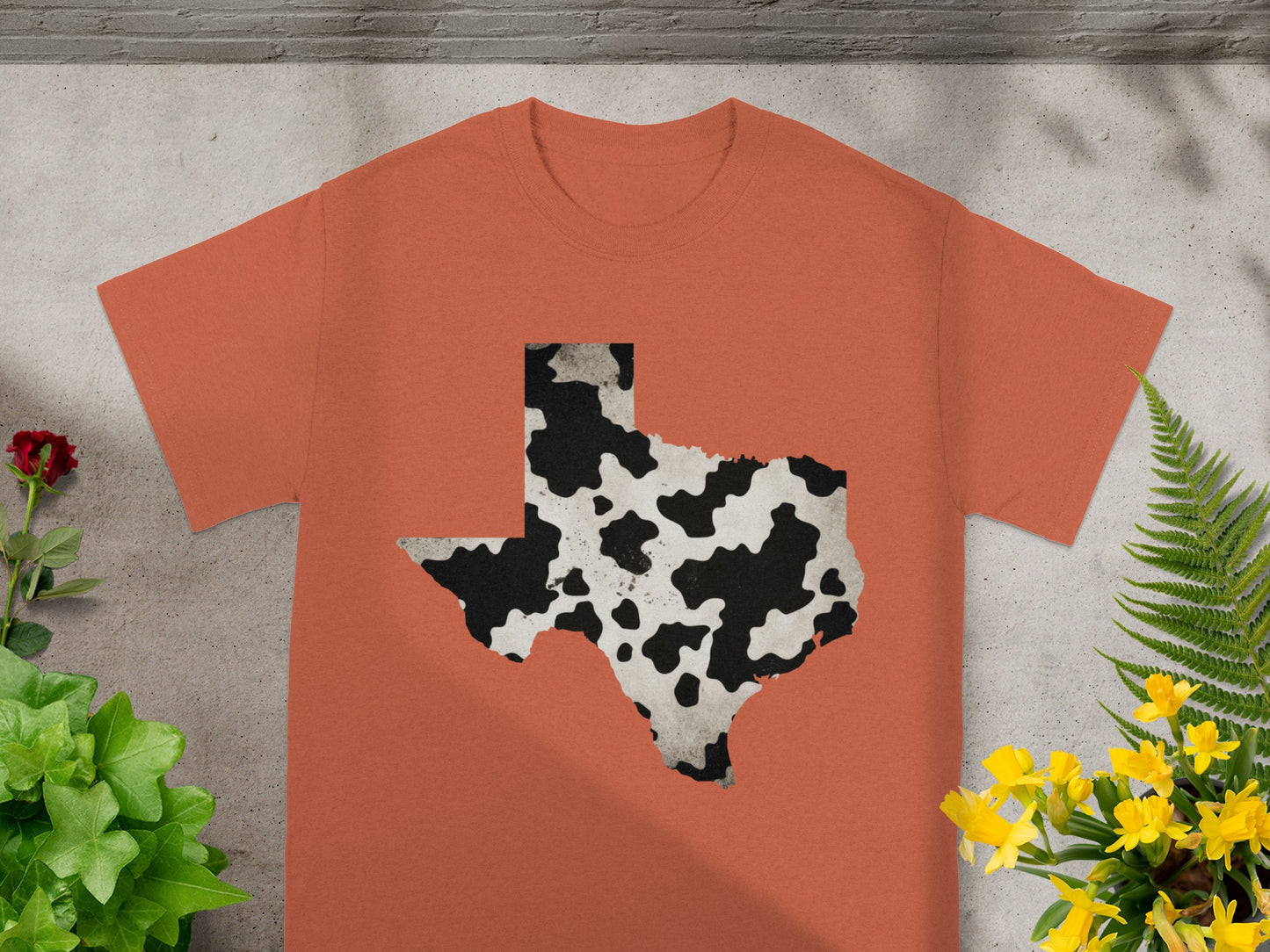 Orange t-shirt with a cow print Texas outline graphic.