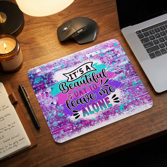 Rectangular mousepad with a purple, blue, and pink abstract design and the text "It's a beautiful day to leave me alone."