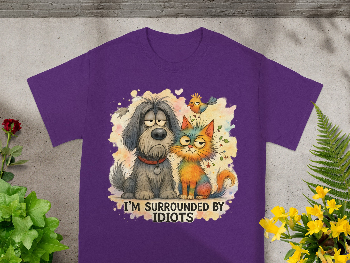 Purple t-shirt with cartoon dog and cat graphic and text "I'M SURROUNDED BY IDIOTS".