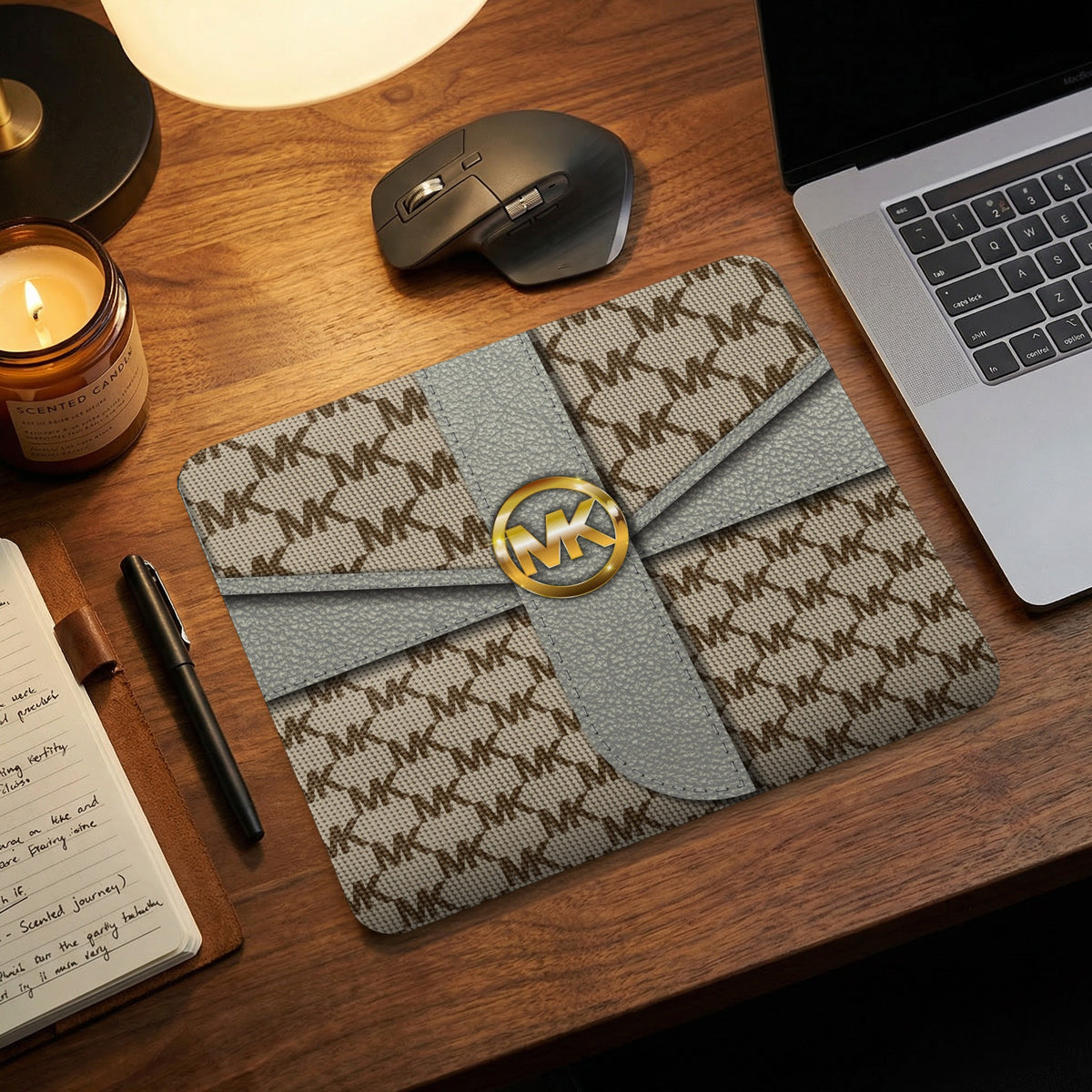 Michael Kors monogram mousepad with gold MK logo on a wooden desk.