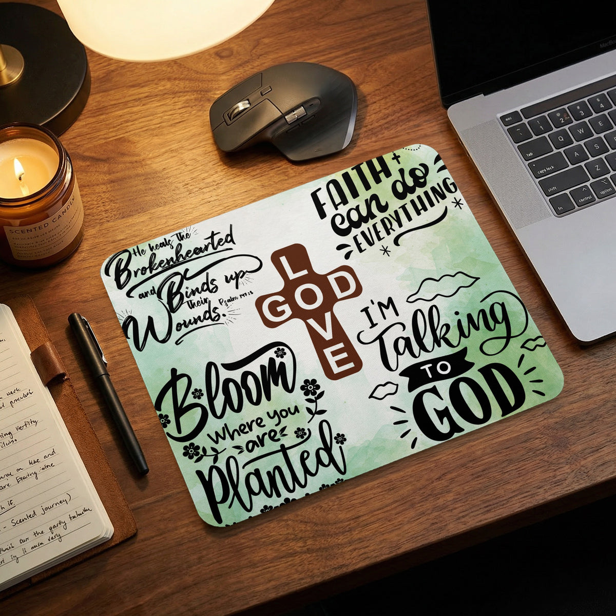 A desk setup featuring a rectangular mousepad with Christian phrases and a central God Love cross graphic.