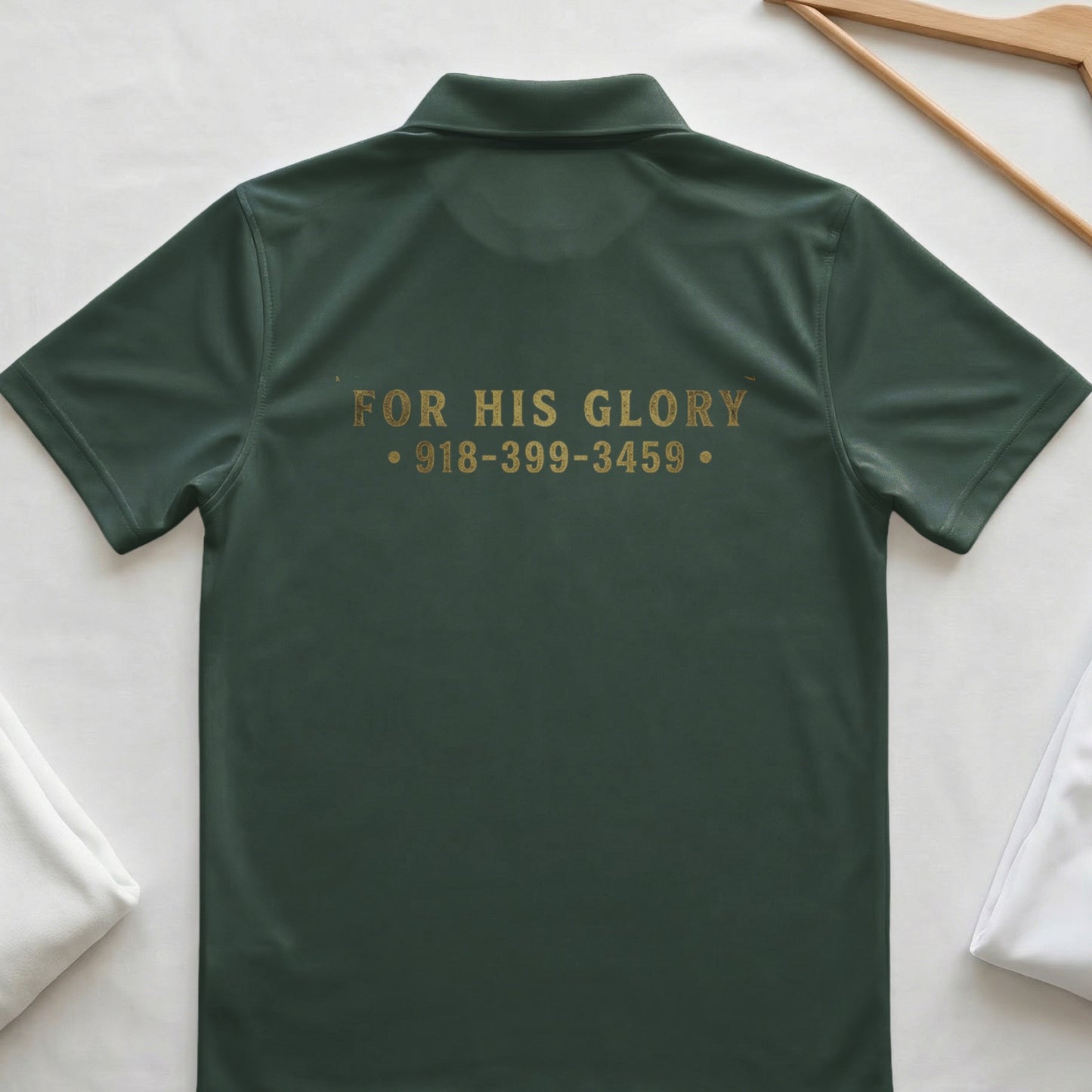 Dark green polo shirt with gold text "FOR HIS GLORY" and phone number.