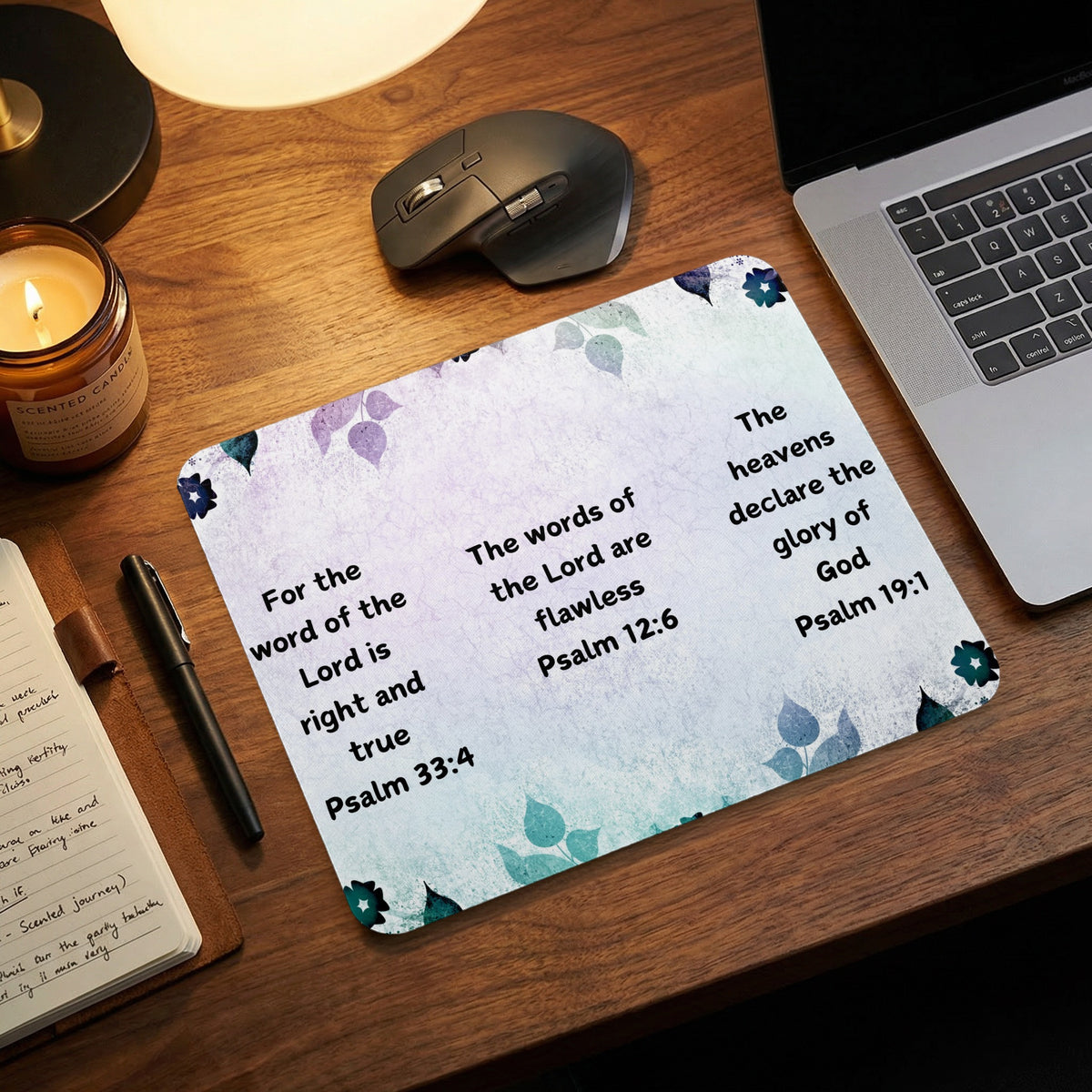 A rectangular mousepad featuring watercolor floral designs and three Bible verses on a wooden desk.