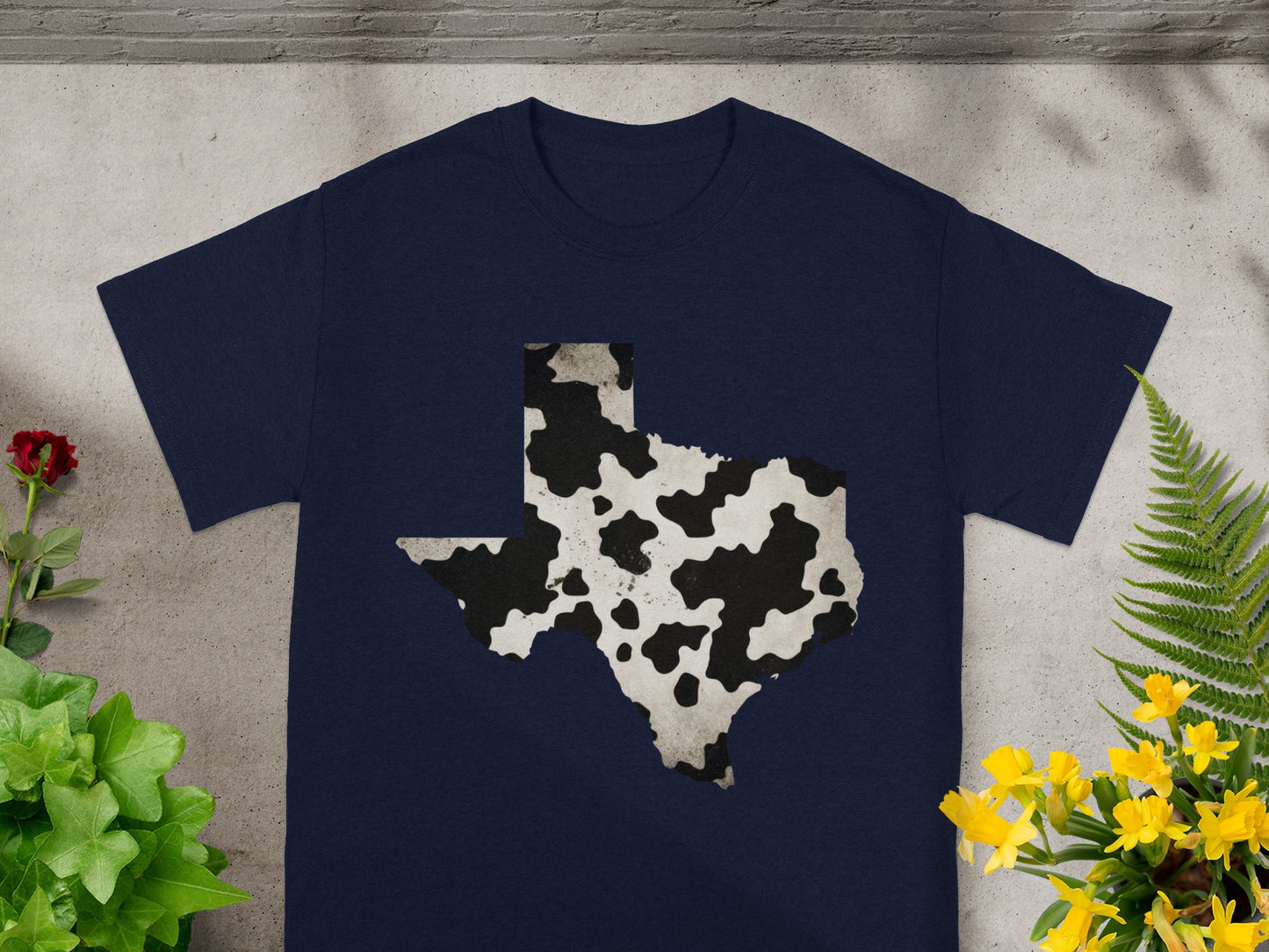 Navy t-shirt with a black and white cow print Texas outline graphic.