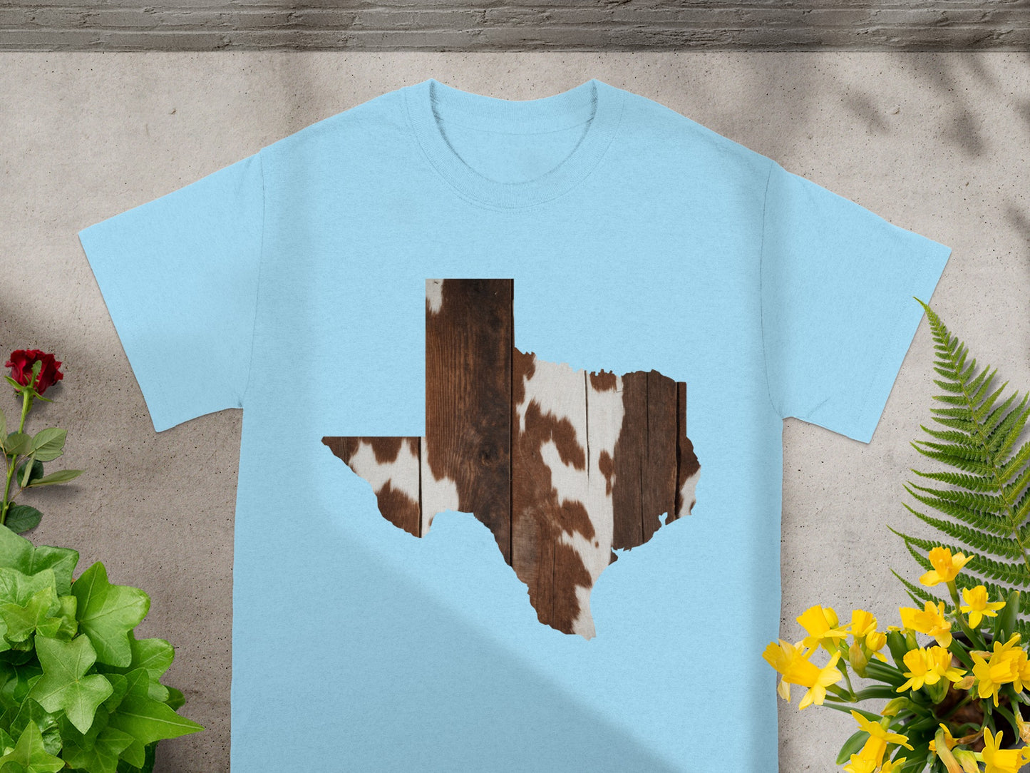 Light blue t-shirt with Texas outline filled with wood and cowhide pattern.