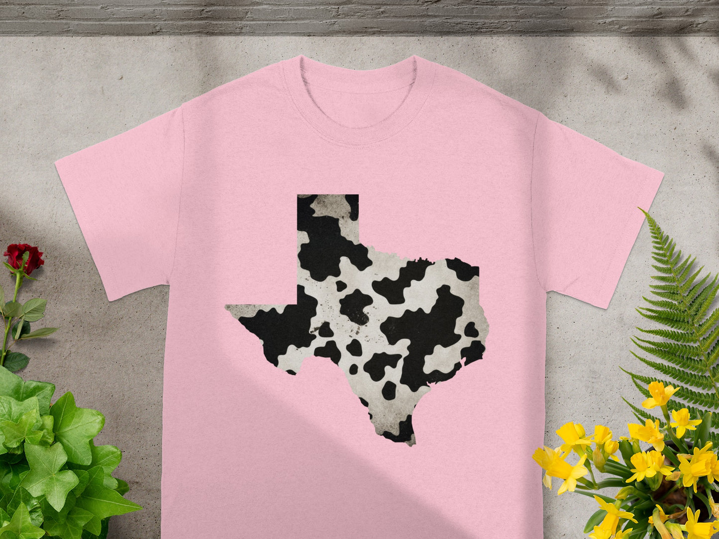 Pink t-shirt with a black and white cow print Texas outline graphic.