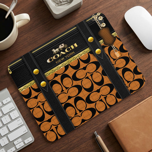 Coach New York mousepad with orange and black logo pattern and gold hardware.