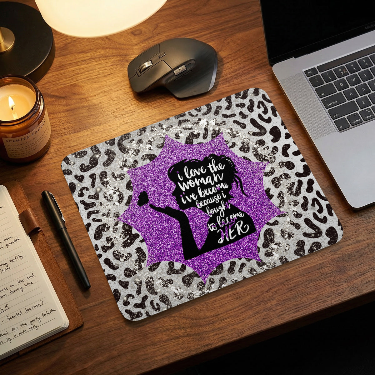 Leopard print mousepad with purple glitter center featuring a silhouette and inspirational quote on a wooden desk.