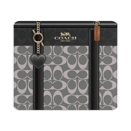 Coach bag with signature pattern and heart charm.