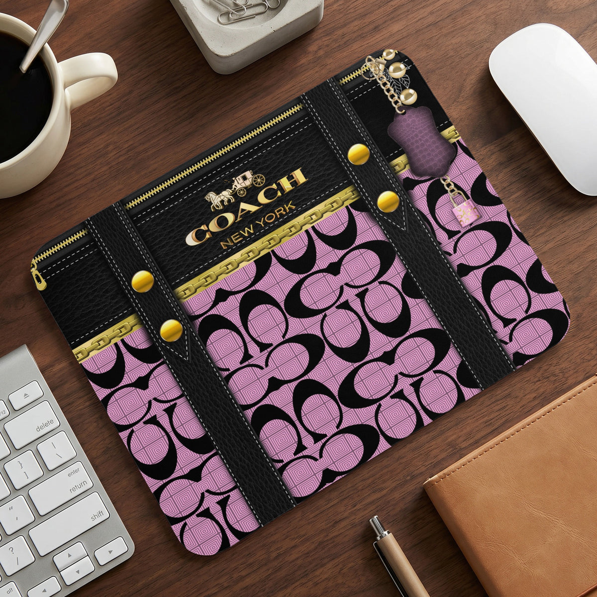 Coach New York mousepad with black and pink logo pattern and gold accents.