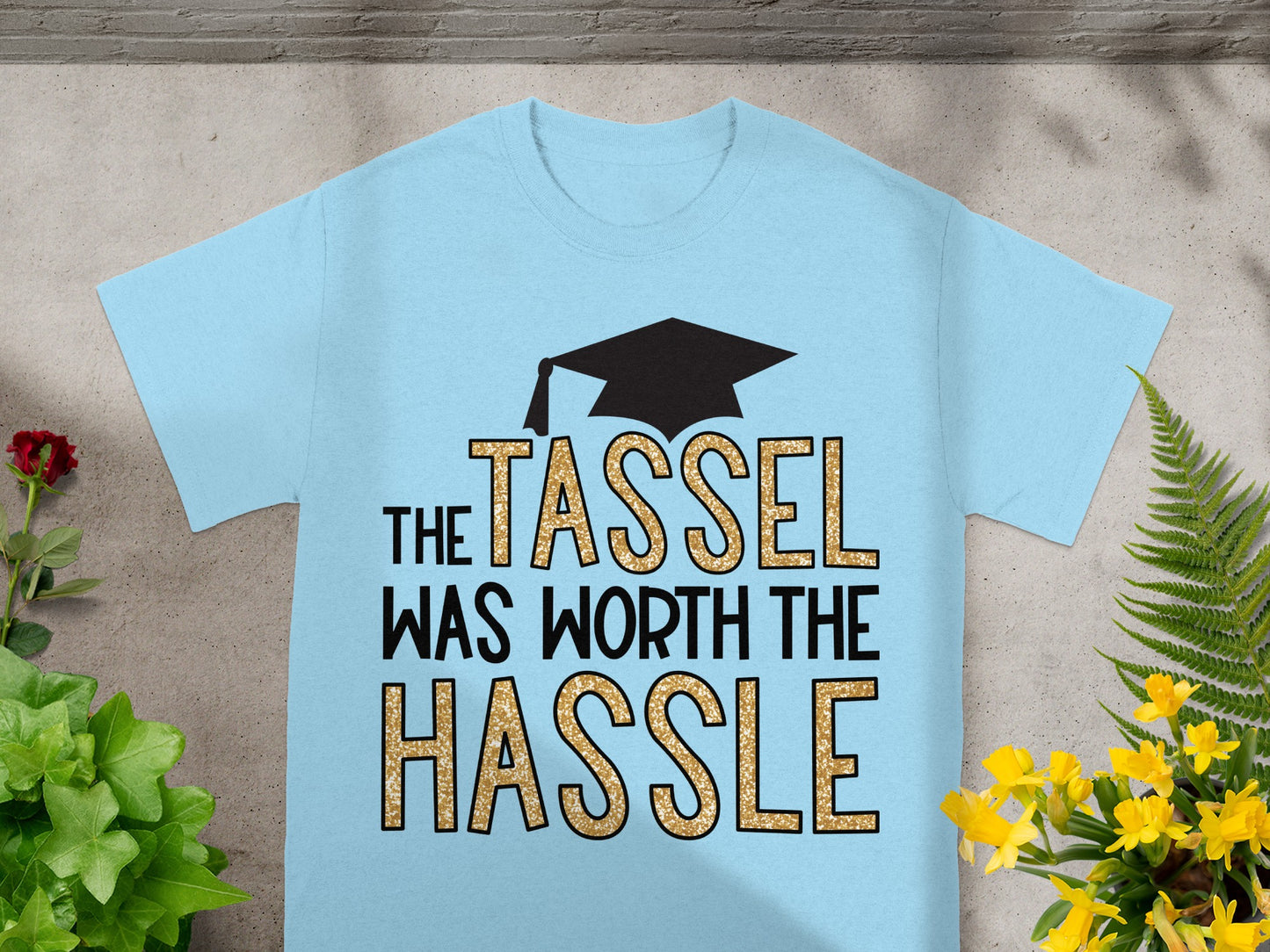 Light blue t-shirt with "The Tassel Was Worth The Hassle" text and a graduation cap.