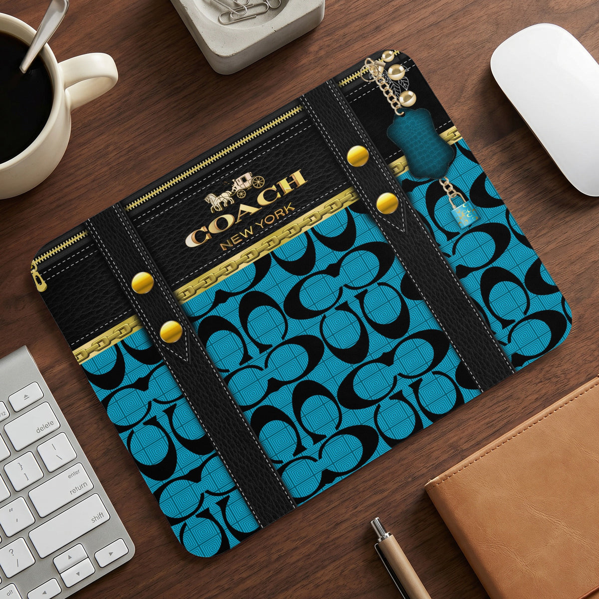 Coach New York logo mousepad with blue pattern and gold hardware on a desk.