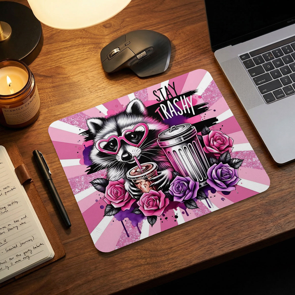A pink mousepad featuring a raccoon wearing heart-shaped glasses, a trash can, roses, and the text Stay Trashy.