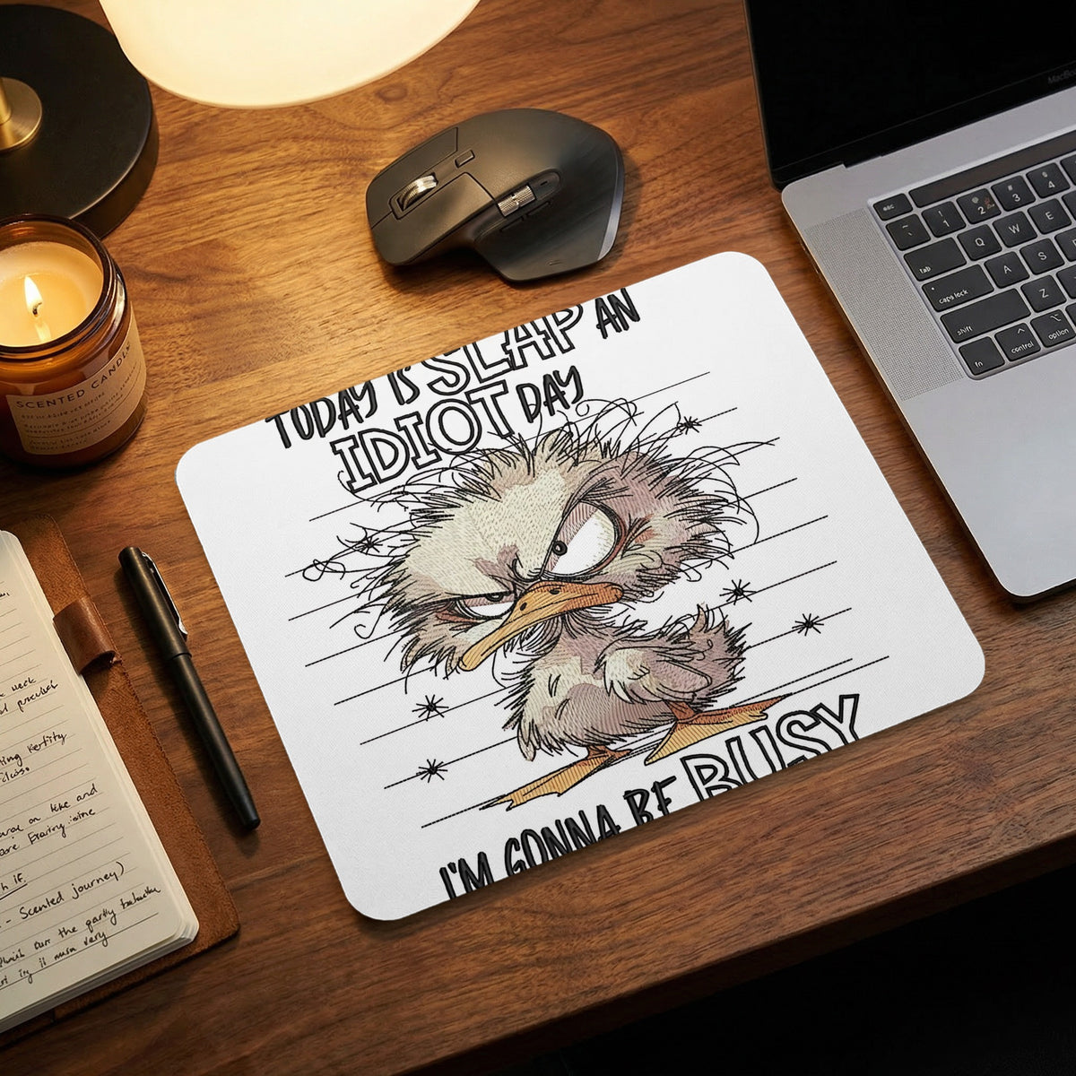 White mousepad on a wooden desk featuring a cartoon duck with messy feathers and the text Today Is Slap An Idiot Day Im Gonna Be Busy.