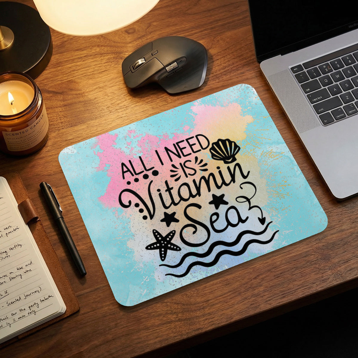 A rectangular mousepad with a watercolor background features the black text All I Need Is Vitamin Sea, flanked by seashells and starfish.