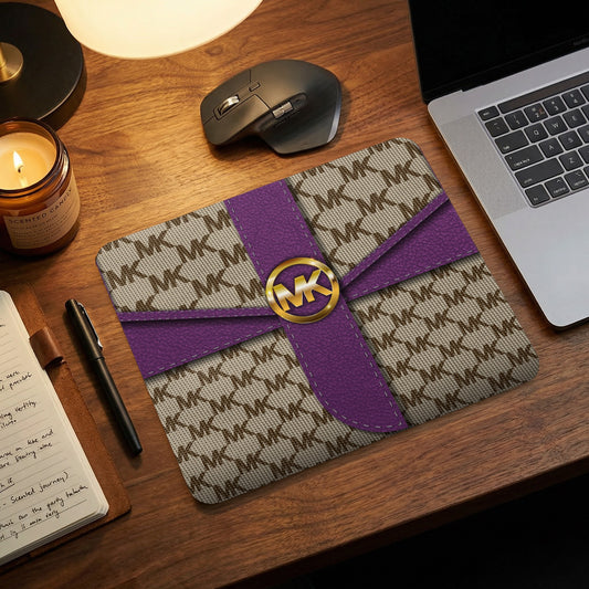 Michael Kors patterned mousepad with purple accents and gold logo.