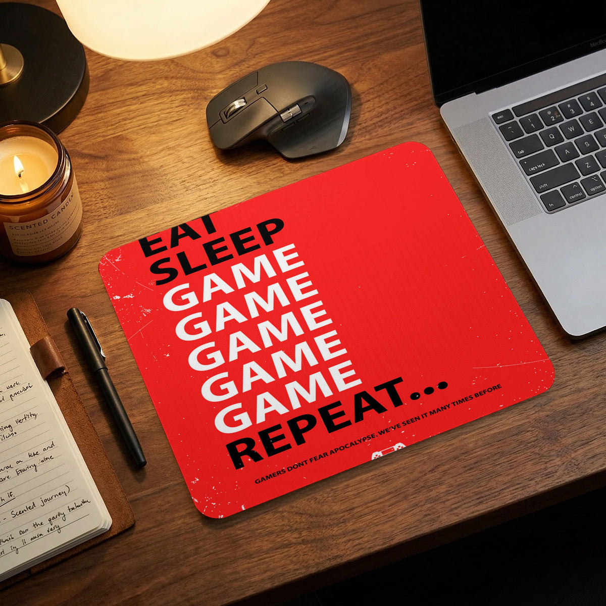 Red rectangular mouse pad with the black and white text Eat Sleep Game Repeat on a wooden desk.
