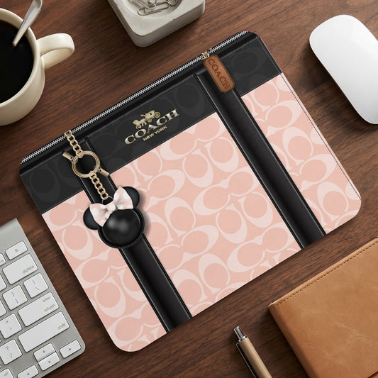 Coach laptop sleeve with pink signature C pattern and Mickey Mouse charm.