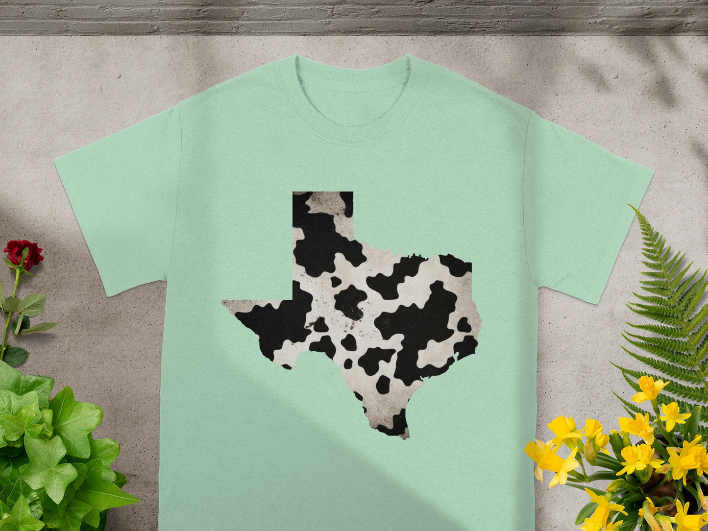Texas map with cow print texture on a light green t-shirt.