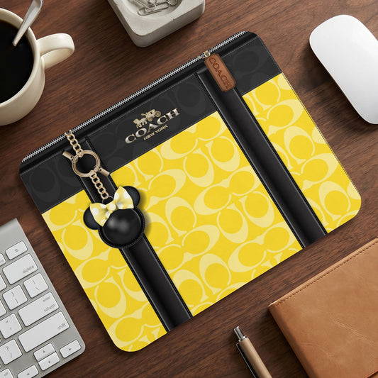Coach clutch with yellow signature pattern and Mickey Mouse charm.