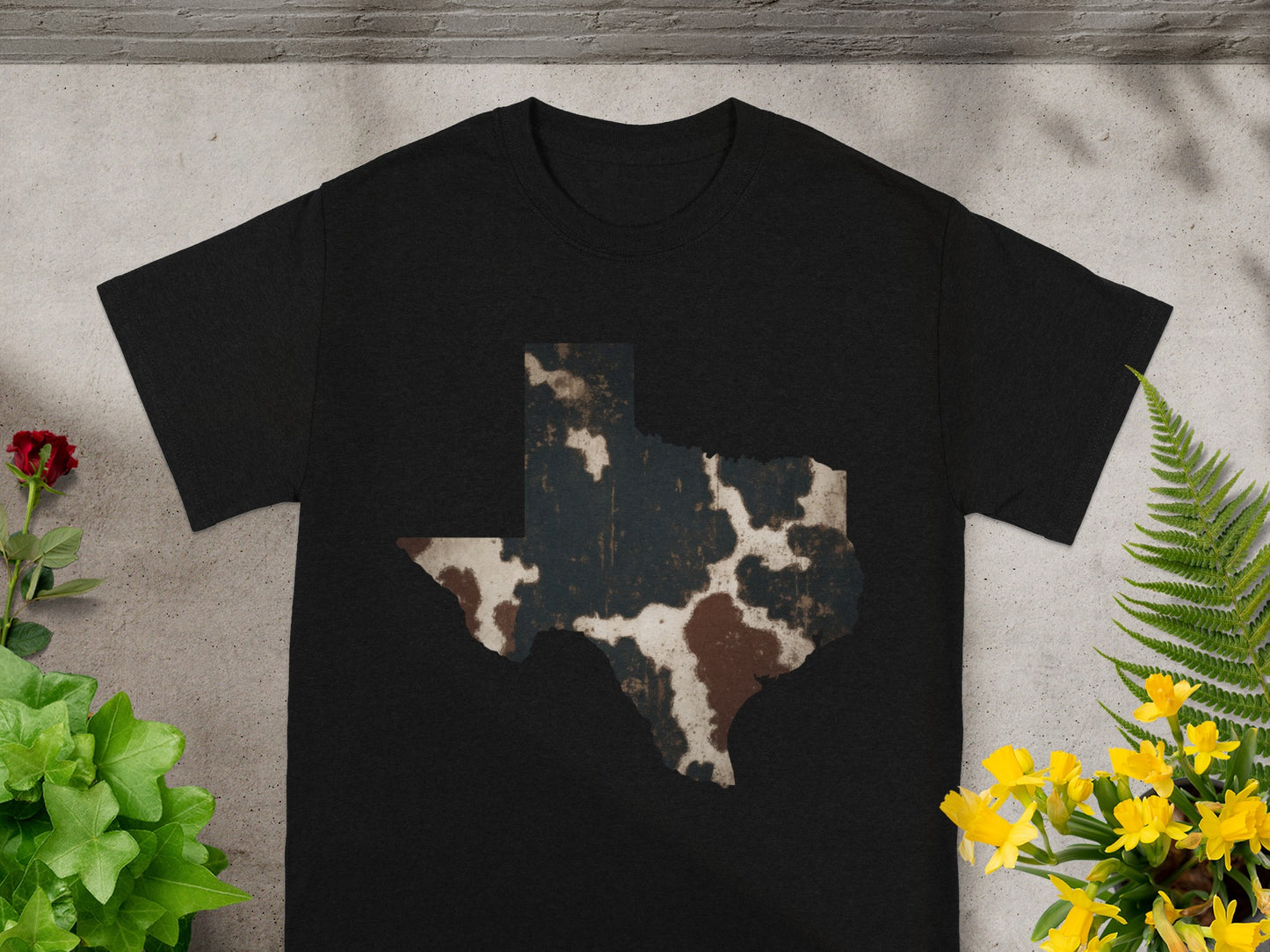 Black t-shirt with a Texas map silhouette in a cowhide pattern.