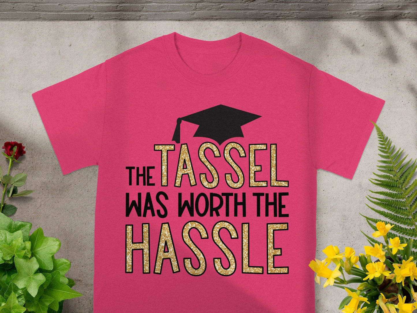 Pink t-shirt with "THE TASSEL WAS WORTH THE HASSLE" in glitter lettering.