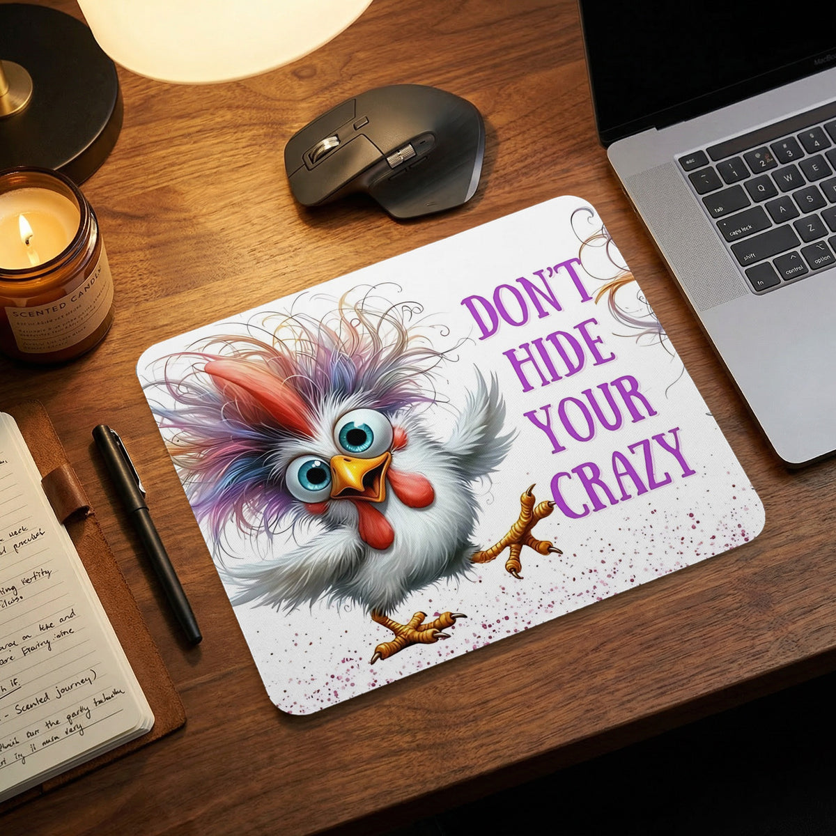 Mousepad on a wooden desk featuring a cartoon chicken and the text "Don't Hide Your Crazy".