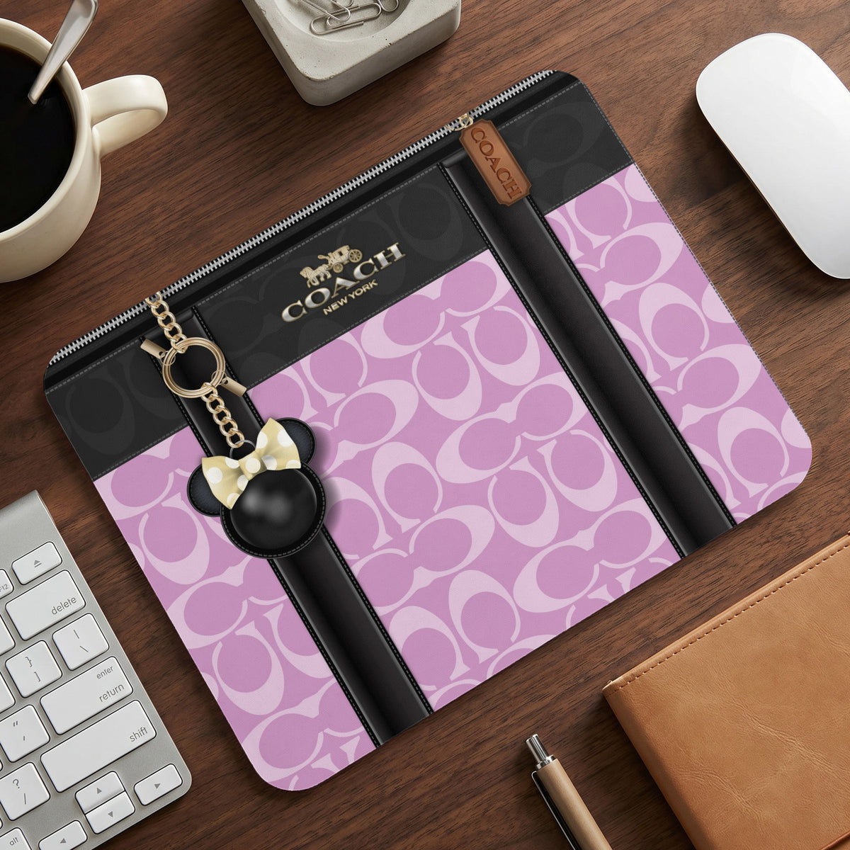 Coach laptop sleeve with pink signature pattern and Mickey Mouse charm.
