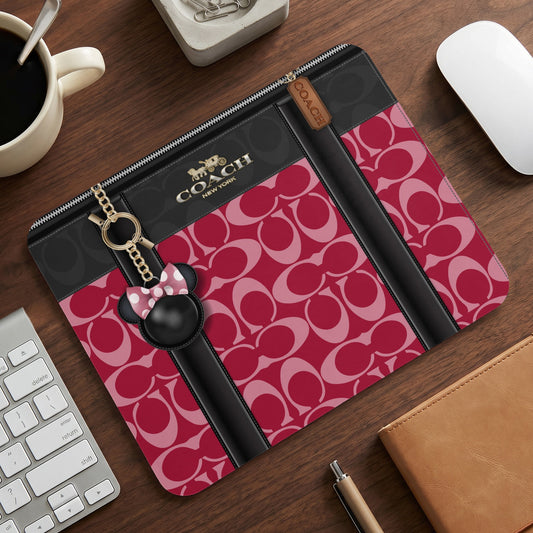 Coach laptop sleeve with signature print and Minnie Mouse charm.