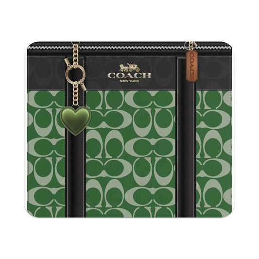 Coach pattern clutch with green heart charm and gold hardware.