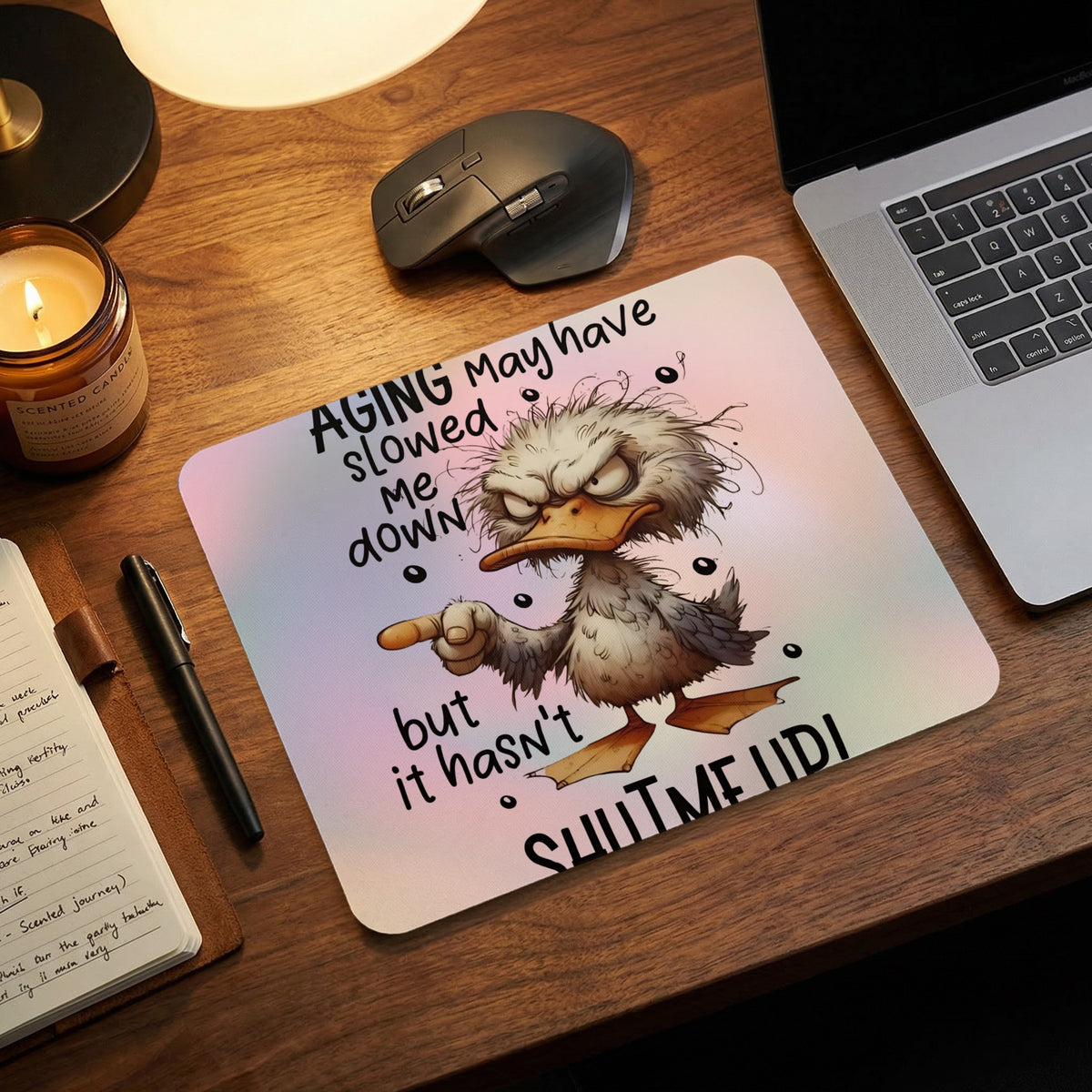 A mousepad on a wooden desk with a grumpy duck graphic and humorous text.