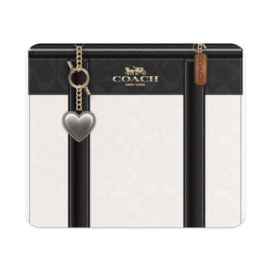Coach New York logo with a silver heart charm and brown leather tag on a patterned bag.