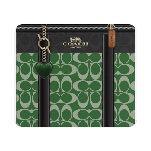 Coach bag with green and white monogram pattern, gold hardware, and heart charm.
