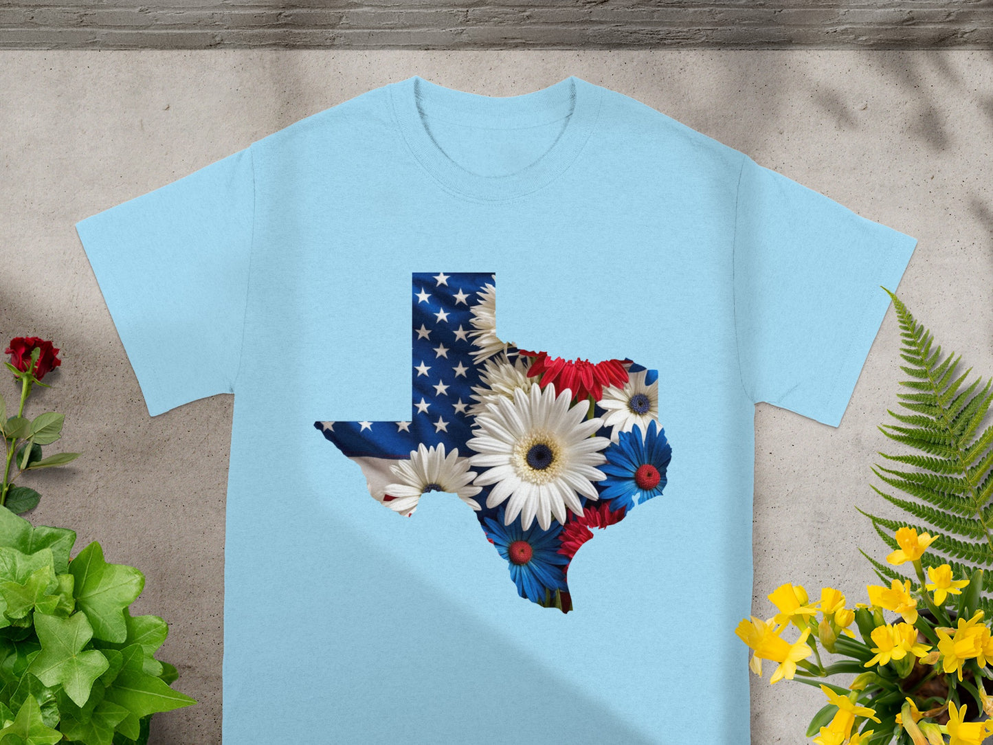 Light blue t-shirt with Texas outline filled with US flag and flowers.