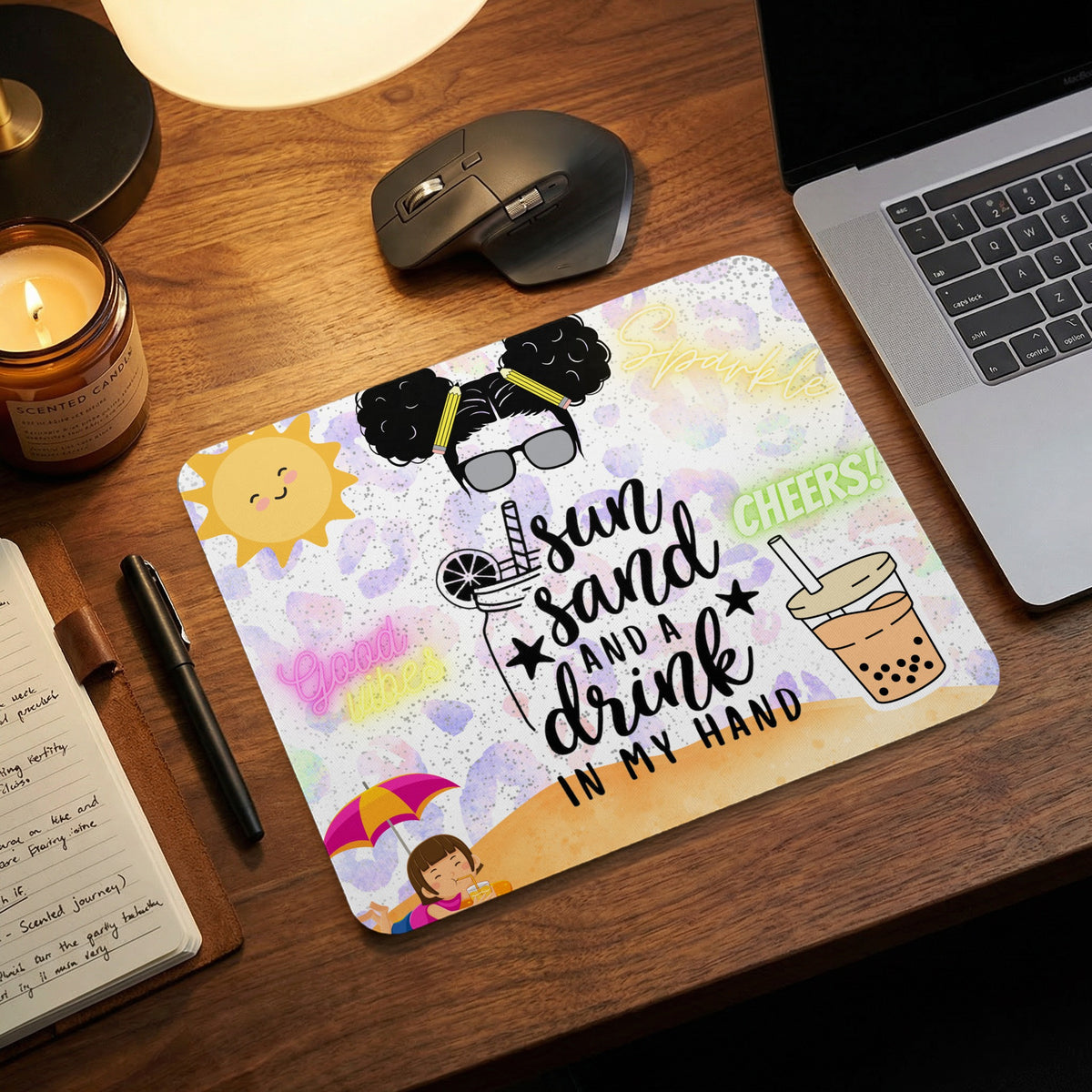 A rectangular mouse pad with a summer design lies on a wooden desk next to a laptop and candle.