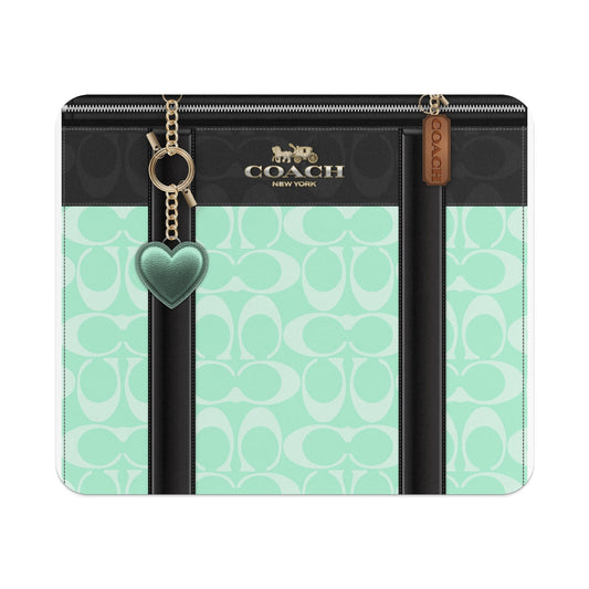 Coach wallet with black and mint green monogram pattern and heart charm.