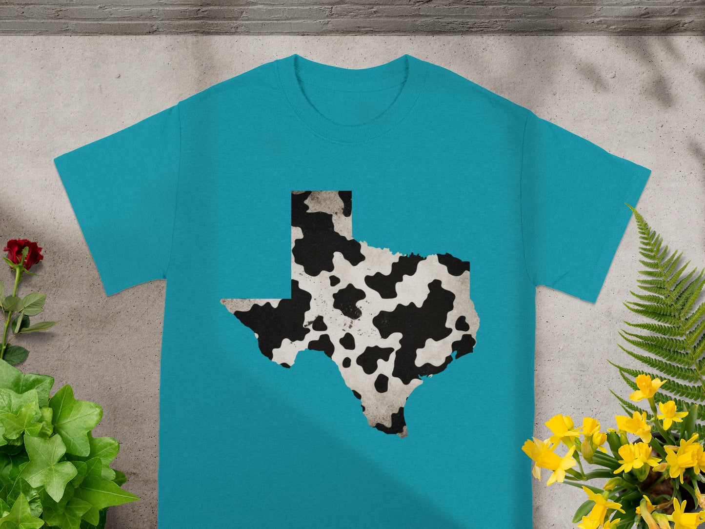 Teal t-shirt with a Texas shape filled with a cowhide pattern.