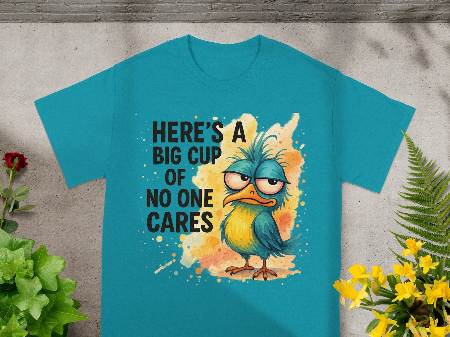Teal t-shirt with cartoon bird and text "Here's a big cup of no one cares."