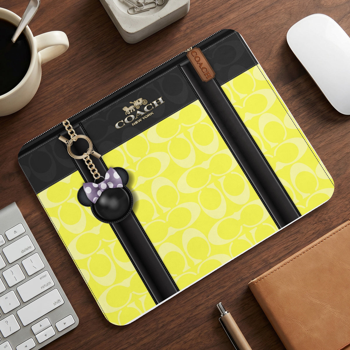 Coach patterned pouch with black accents, gold logo, and Minnie Mouse charm.