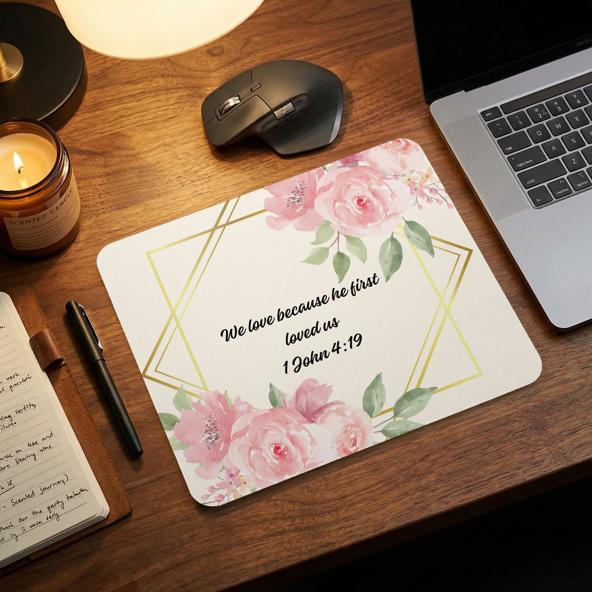 A rectangular mousepad featuring pink watercolor roses, gold geometric frames, and the Bible verse 1 John 4:19.
