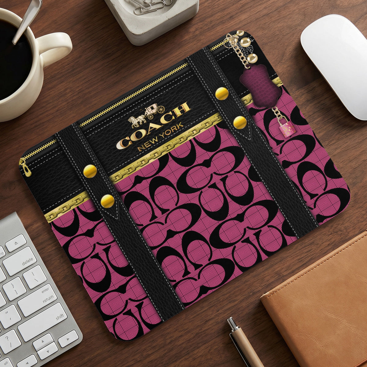 Coach logo mousepad with pink signature pattern and gold chain detail.