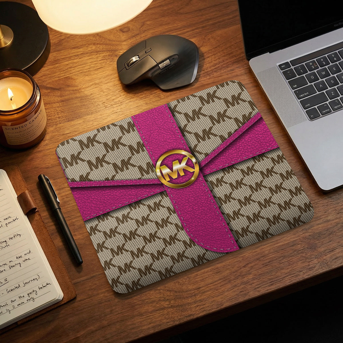 Michael Kors logo mousepad with pink ribbon design on wooden desk.