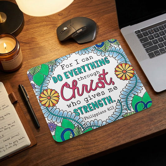 A rectangular mousepad featuring floral artwork and the Bible verse Philippians 4:13 on a wooden desk.