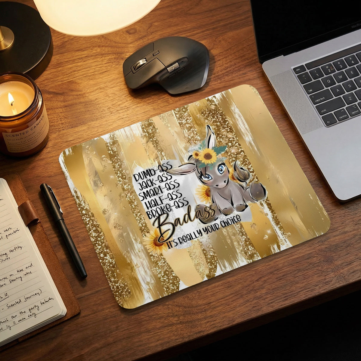 Gold mousepad with a cartoon donkey, sunflowers, and humorous text on a wooden desk.