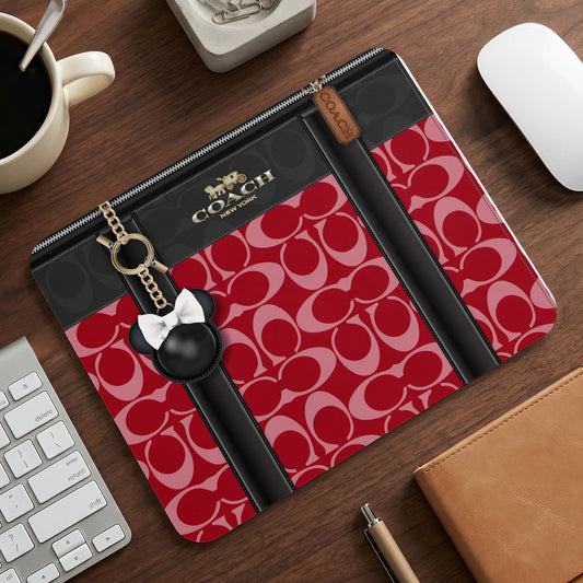 Coach laptop sleeve with signature print, black accents, and mouse charm.