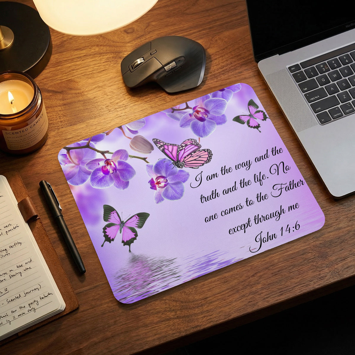 A rectangular mousepad featuring purple orchids, butterflies, and the Bible verse John 14:6 rests on a wooden desk.