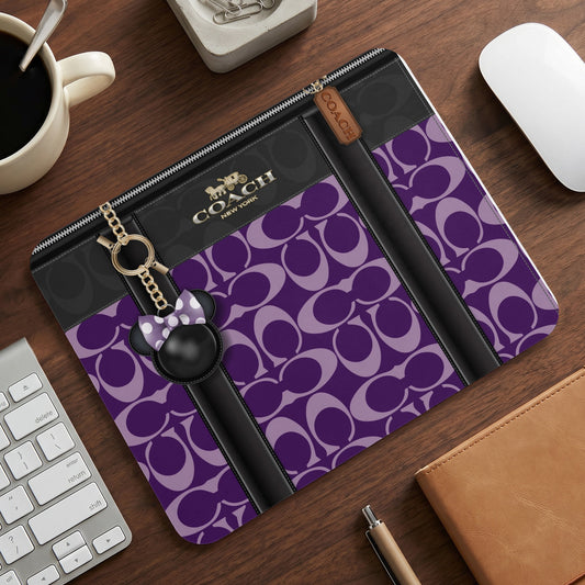 Coach laptop sleeve with purple monogram pattern and Minnie Mouse charm.