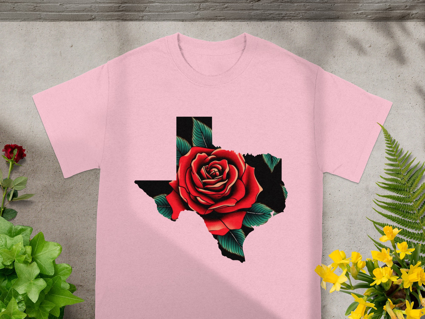 Pink t-shirt with a Texas outline filled with a red rose and green leaves graphic.
