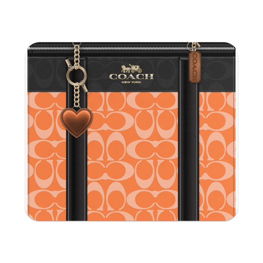 Coach bag with orange C logo pattern, black trim, and heart charm.